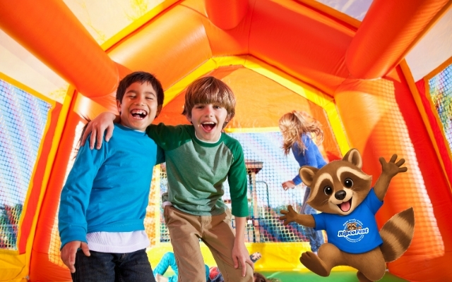 Kids jumping in a bounce house with Rippy jumping with them.