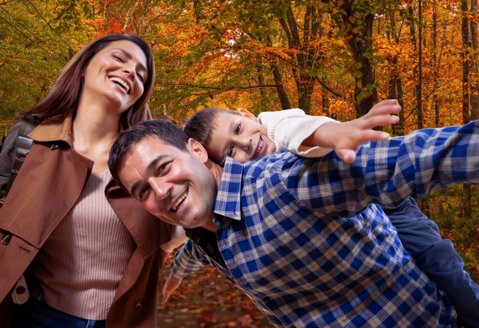 a family playing airplane in a fall background outside