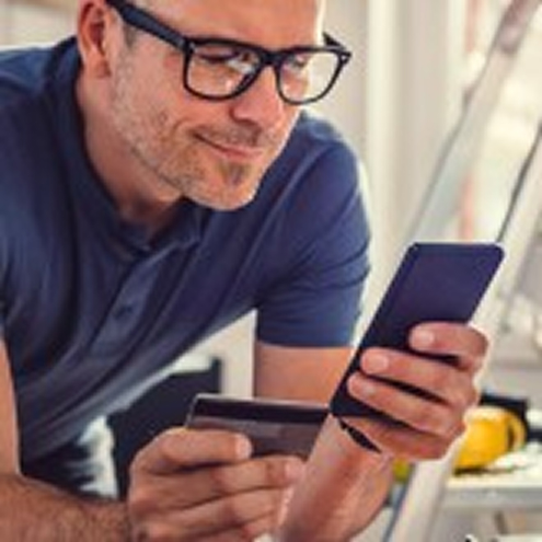 A man in glassing holding a card in one hand and a phone in the other