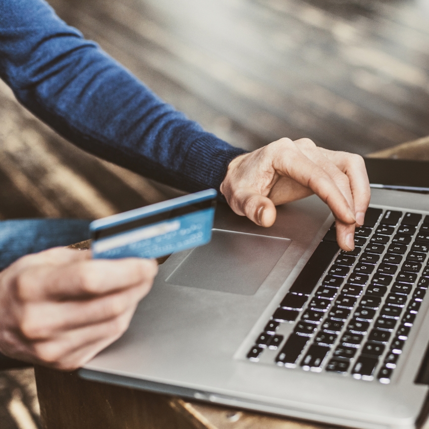 close-up of someone holding a card over a laptop